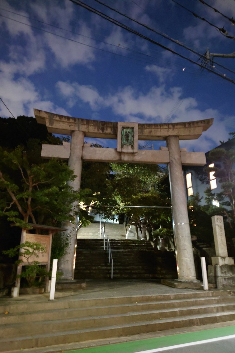 夕方の空の下、石段の上に立つ紅葉八幡宮の石の鳥居