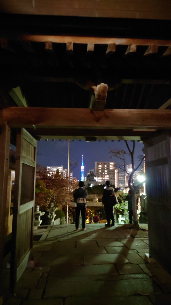 夜、神社の門の向こうに青く光る福岡タワーが見える